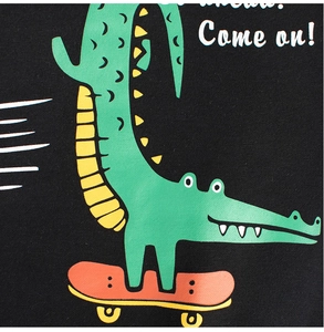 Détail d'un sweat-shirt noir pour enfant avec un crocodile vert sur un skateboard orange