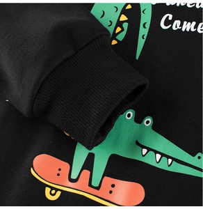 Détail des poignets côtelés et de l'imprimé crocodile sur un sweat-shirt noir enfant