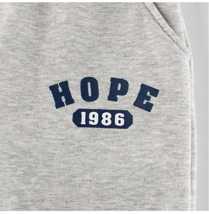 Detailed view of gray knit fabric and vintage blue HOPE 1986 letter print on kids pants