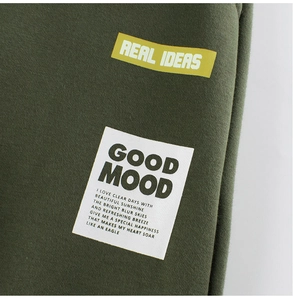 Détail du tissu de sweat vert armée avec les slogans imprimés REAL IDEAS et GOOD MOOD