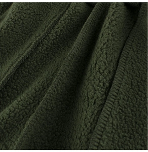 Détail macro du tissu polaire vert foncé montrant la texture douce et la couture nette