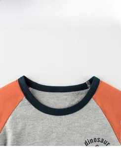 Détail du col rond côtelé sur un t-shirt en coton à manches raglan et motif dinosaure