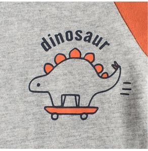 Détail du tissu gris avec motif dinosaure sur skateboard et manche orange contrastée
