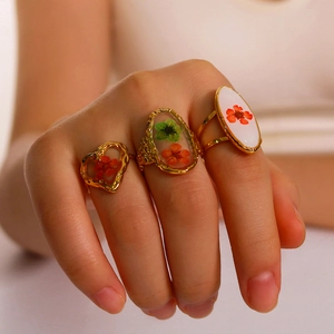 Set di tre anelli in resina dorata con fiori secchi veri indossati da una donna