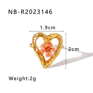 Dettaglio anello a cuore dorato con vero fiore essiccato arancione e metallo martellato