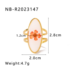 Dettaglio dell'anello in acciaio dorato con piccolo fiore d'arancio su base ovale