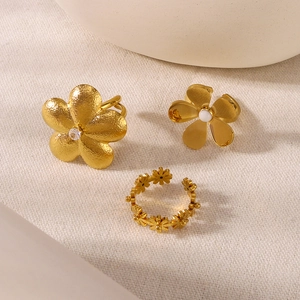 Golden flower ring set with pearls and zircon crystals on white fabric background