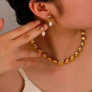 Elegant gold scallop shell necklace and drop pearl earrings jewelry set on a model