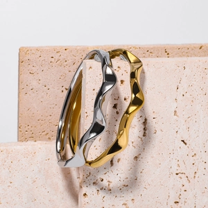 Polished silver and gold wavy mobius bracelets on stone board in a modern display