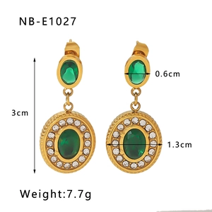 Detail shot of vintage gold earrings with green gemstones and white zircon crystals