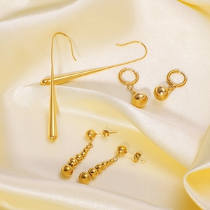 Elegant gold teardrop and bead stainless steel earrings set on yellow silk fabric