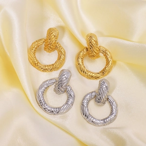 Boucles d'oreilles vintage en acier inoxydable doré et argenté sur fond de soie jaune