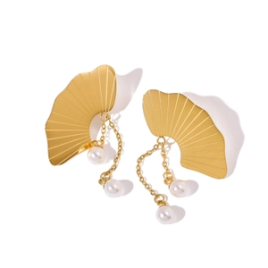 Détail de boucles d'oreilles ginkgo dorées avec texture et perles blanches pendantes
