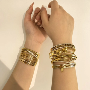 Set of gold-plated fashion bangles featuring zipper and floral cutout designs on wrist
