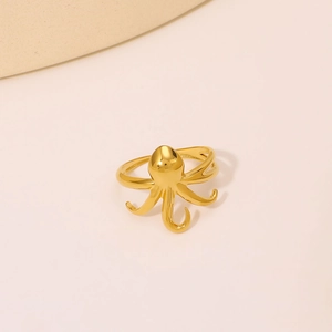 Minimalist gold plated stainless steel octopus ring with polished finish on beige surface