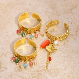 Three-piece gold fringe ring set with colorful beads and shell charm on stone surface