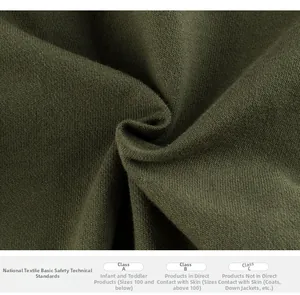Close-up of dark green cotton knit fabric texture with textile safety standards chart