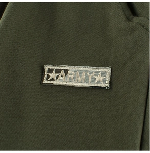 Close-up of deep green knit fabric with army-themed embroidery patch and stars