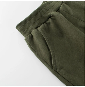 Detail of olive green kids joggers featuring elastic waistband and reinforced side pockets