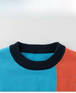 Vue détaillée du col ras du cou côtelé et du patchwork orange-bleu de ce pull pour enfant