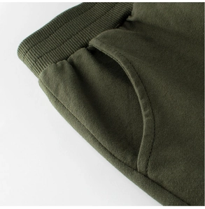 Detail view of olive green cotton sports pants showing elastic ribbed waist and side pocket
