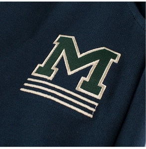 Detail der Varsity-M-Stickerei auf dunkelblauer Baumwoll-Sporthose für Kinder