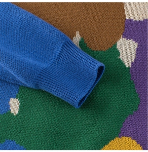Detail of knitted sweater showing ribbed cuffs and colorful abstract geometric pattern