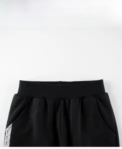 Détail du pantalon de jogging noir pour enfant avec taille élastique et rayures latérales