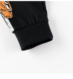 Détail des poignets côtelés élastiques sur pantalon enfant noir avec motif voiture orange