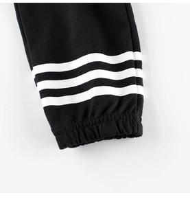 Macro view of black knit jogger cuffs with elastic ribbing and iconic white triple stripes