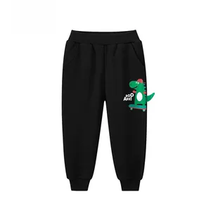Detail van de zwarte kinderjoggingbroek met groene dinosaurusprint en elastische boorden