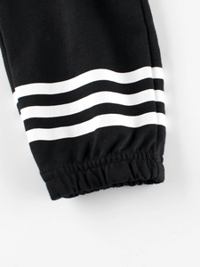 Close-up of boys' black cotton joggers featuring elastic ribbed cuffs and white sporty stripes