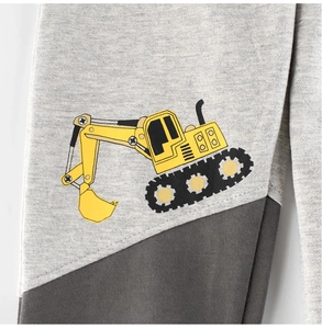 Close-up of children's grey joggers featuring a yellow cartoon excavator print and patchwork