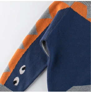 Detail of navy blue kids sweater sleeve with orange dinosaur fin patterns and soft knit