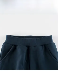Detailed view of elastic waistband and pockets on navy blue cartoon dinosaur pants