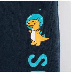 Detail of navy blue knit kids pants featuring a yellow space dinosaur and teal letter S