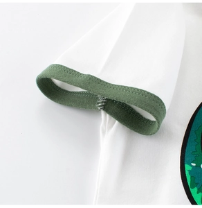 Détail de la manche d'un t-shirt blanc avec bord-côte vert et finitions de couture précises