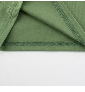 Close-up of green cotton kids t-shirt hem featuring high-quality double-needle stitching