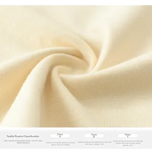 Detailed close-up of soft warm beige knitted cotton fabric showing texture and safety labels