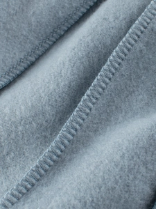 Gros plan sur un polaire gris-bleu épais montrant une texture dense et des coutures soignées