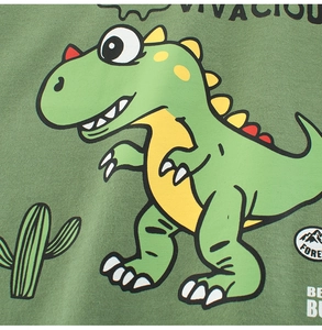 Dettaglio ravvicinato della stampa con dinosauro e cactus su maglietta in cotone verde da bambino