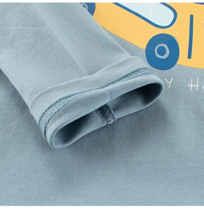 Close-up of cotton sleeve cuff and yellow bus print on a blue long-sleeve kids T-shirt