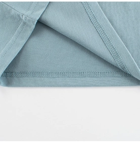 Macro view of double-stitched hem and overlock seam on light blue cotton kids t-shirt