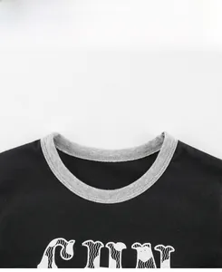 Détail d'un t-shirt noir pour enfant montrant le col gris côtelé et les coutures soignées