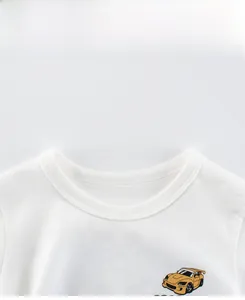 Détail du col rond et de l'imprimé voiture jaune sur le t-shirt blanc pour enfants