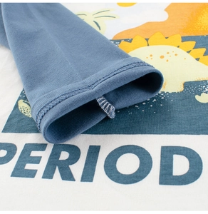 Détail des coutures aux poignets et motif dinosaure coloré sur le t-shirt enfant