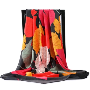 Détail d'un foulard en satin aux fleurs vives avec texture soyeuse sur un cadre noir