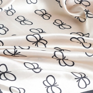 Detailed close-up of butterfly print satin scarf fabric with elegant silk texture