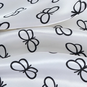 Macro shot of silk satin fabric showing black butterfly print and glossy texture