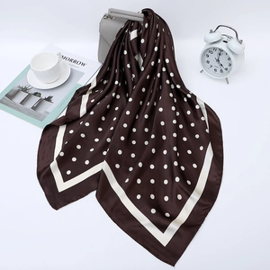 Deep coffee silk scarf with white polka dots draped on a stylish grey handbag